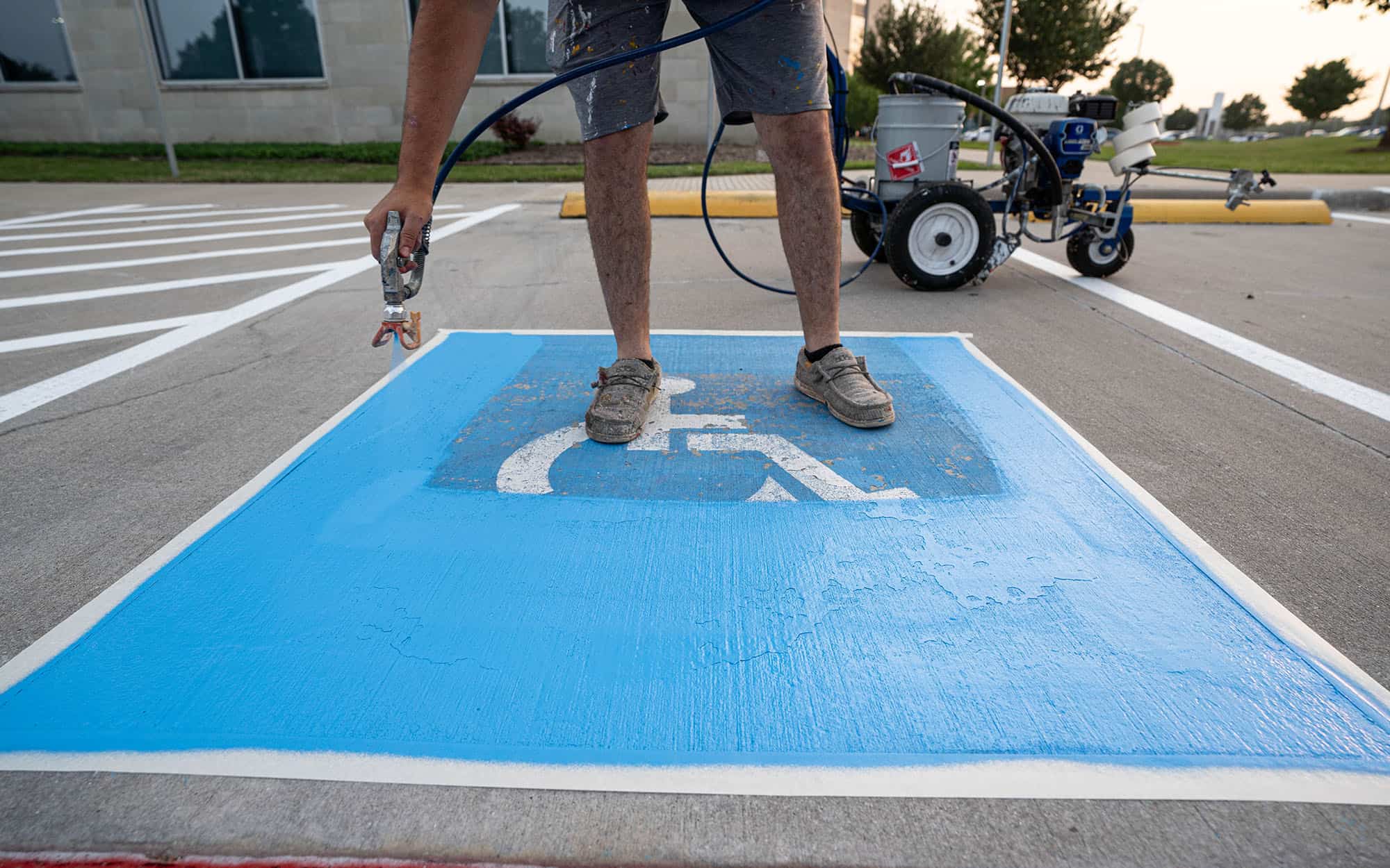 Front view of someone painting handicapped parking space