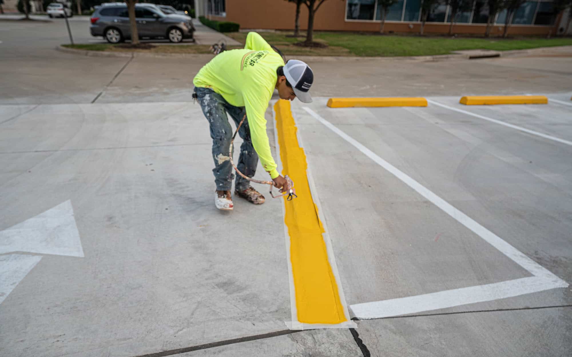 Side view of man in boots painting a parking lot stripe