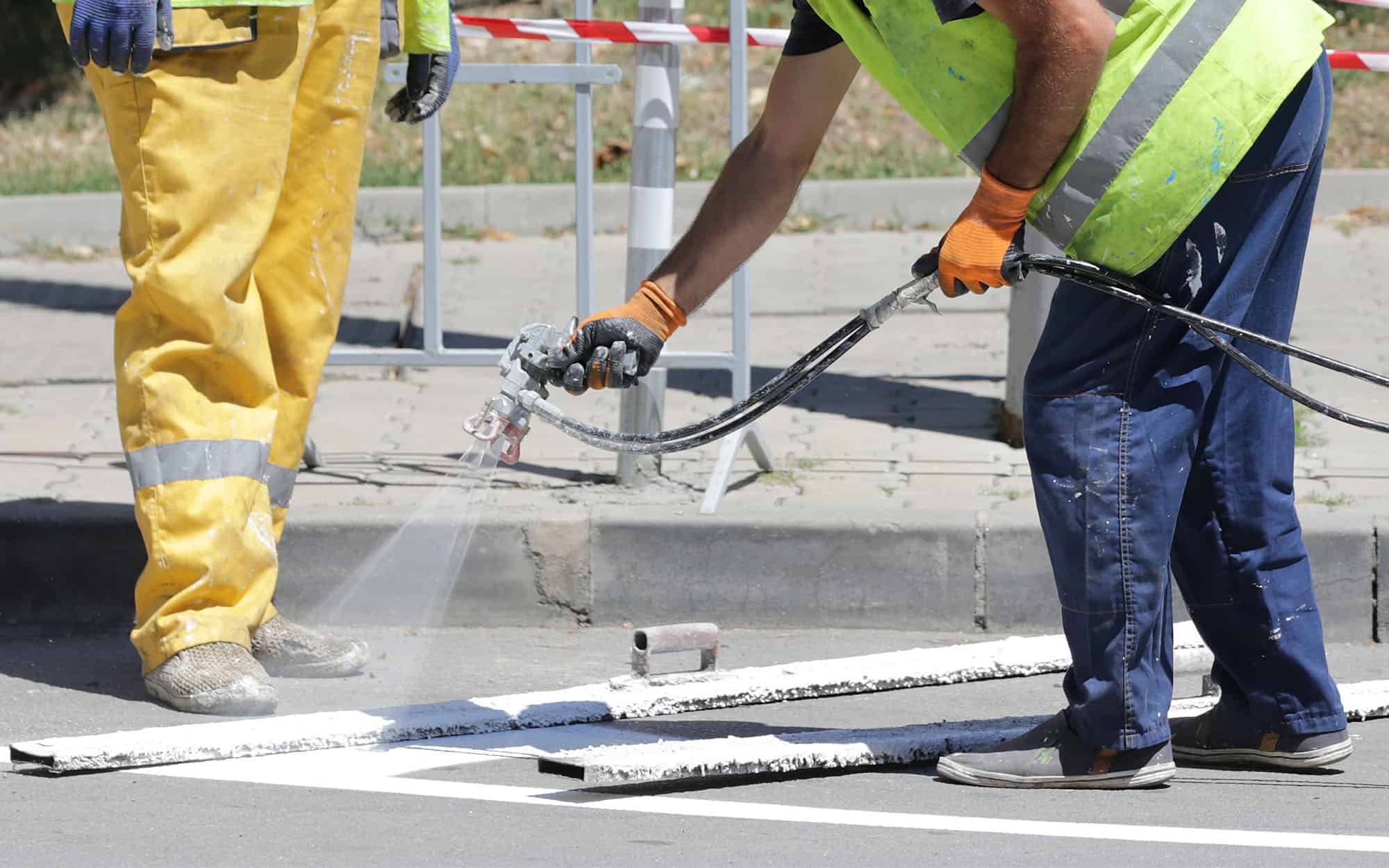 Side view of two workers painting parking lot