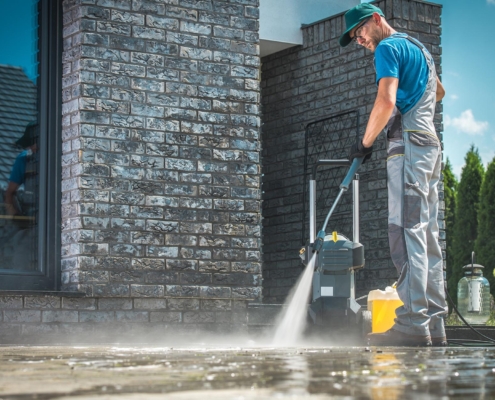 Worker power washing commercial street